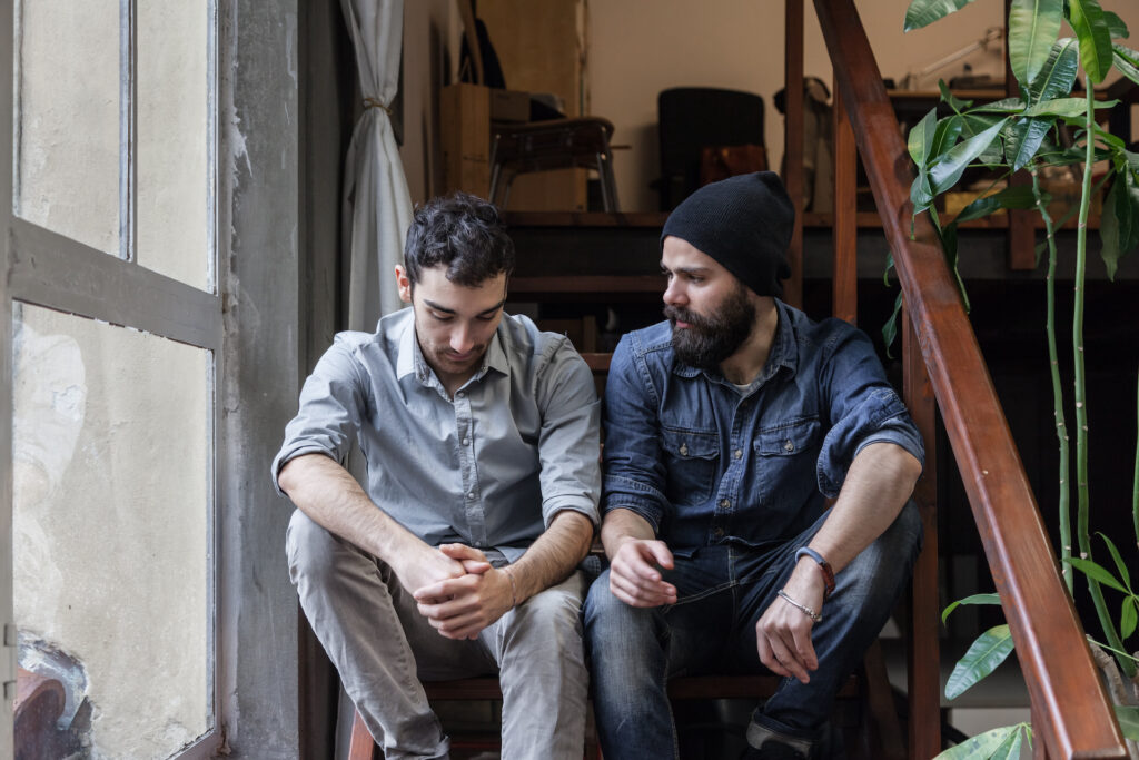 two men supporting one another talking about loved one dying from an overdose