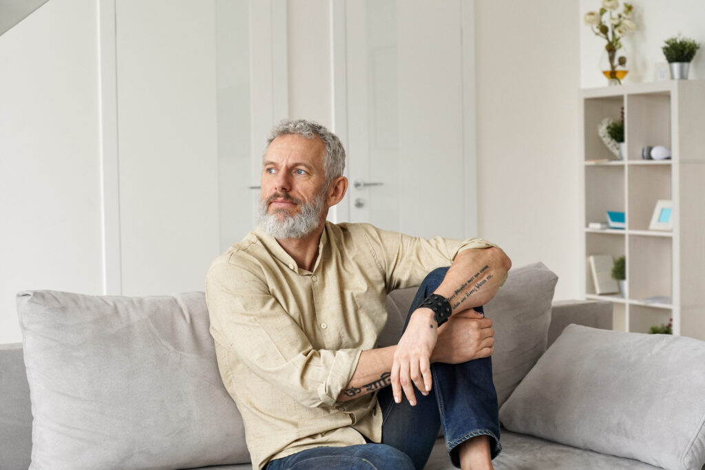 Older man on couch pondering how to be immune to addiction