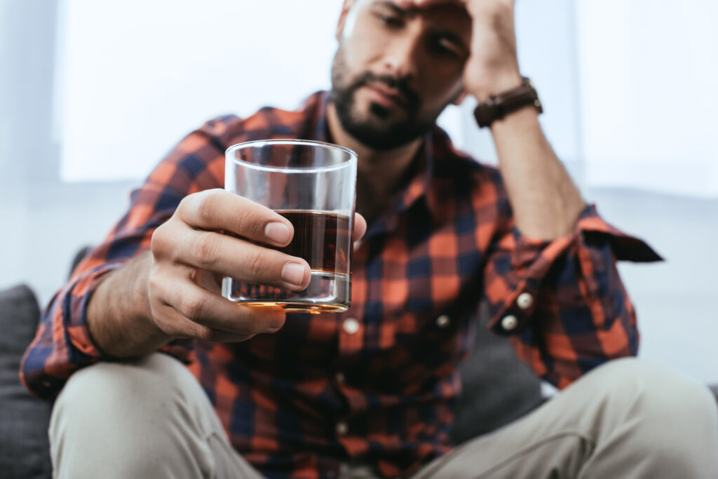 man sitting with glass of alcohol
