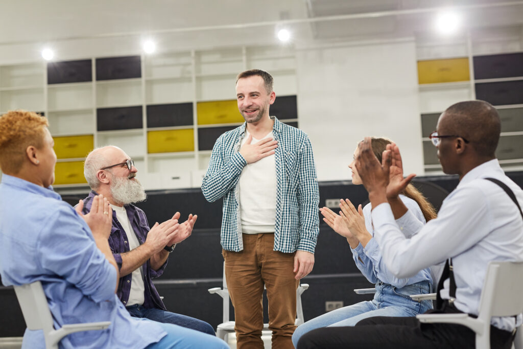 man standing receiving support in SMART Recovery meeting