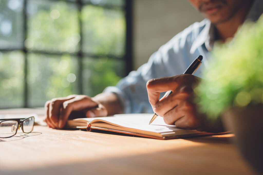 man writing in a journal about life