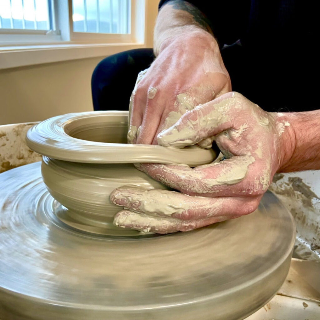 man working with clay on a pottery wheel in a clay workshop