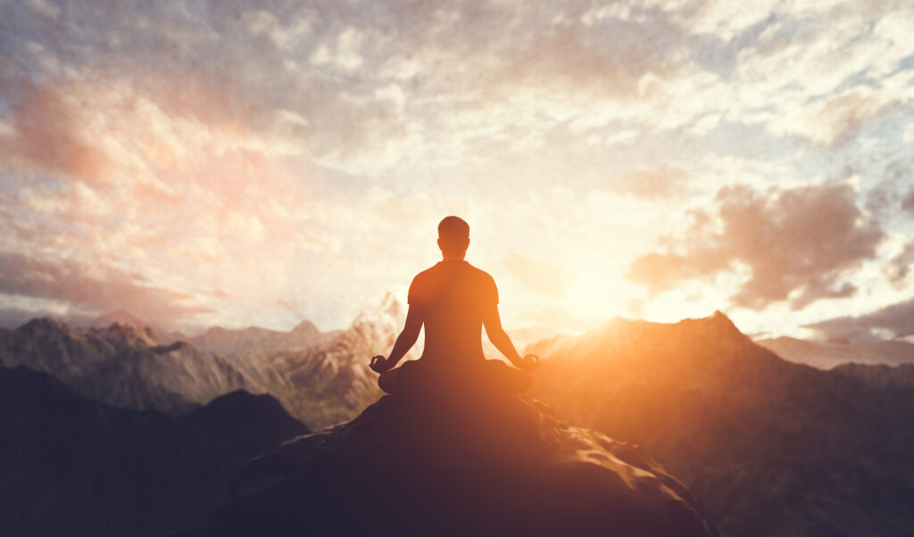 man connecting with spirituality atop a mountain