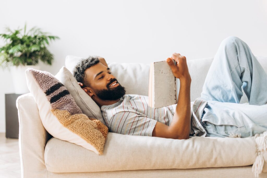 man reading book on couch